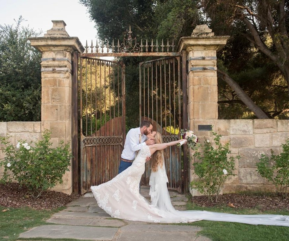 Just married couple kissing in front of a brick and iron gate